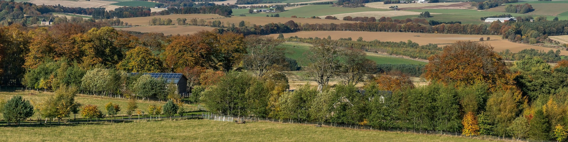 A rural landscape with rolling hills, wind turbines, and a solar farm.
