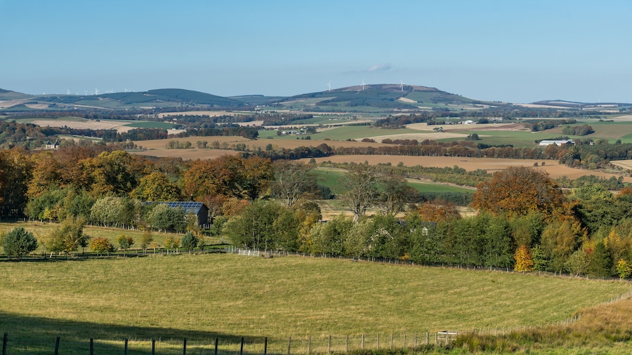 A rural landscape with rolling hills, wind turbines, and a solar farm.