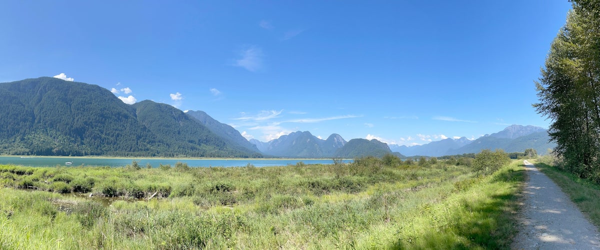 A mountain landscape with a clear sky, a lake, and a path.