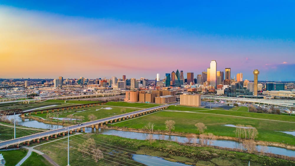 A city skyline with a prominent tower, a river, and a bridge.