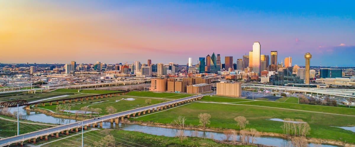 A city skyline with a prominent tower, a river, and a bridge.