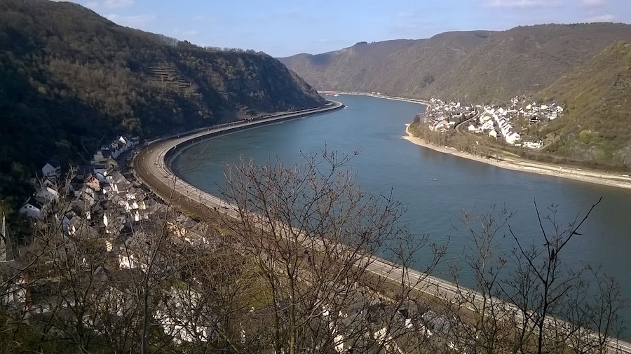 A river curving through a mountainous landscape with a bridge and a village on the right bank.
