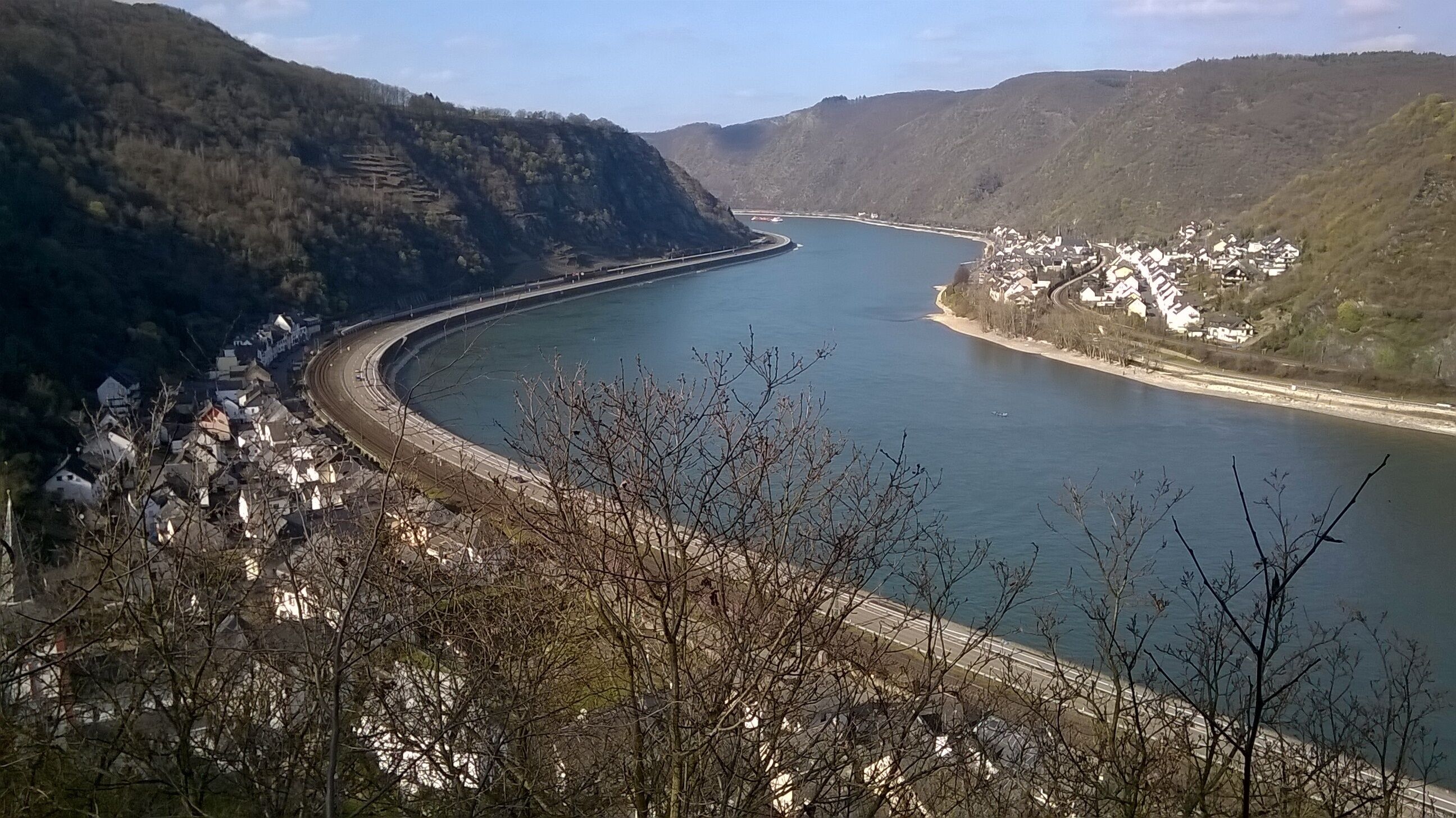 A river curving through a mountainous landscape with a bridge and a village on the right bank.