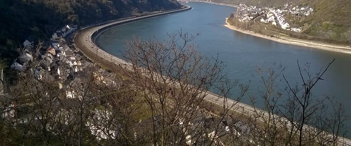 A river curving through a mountainous landscape with a bridge and a village on the right bank.
