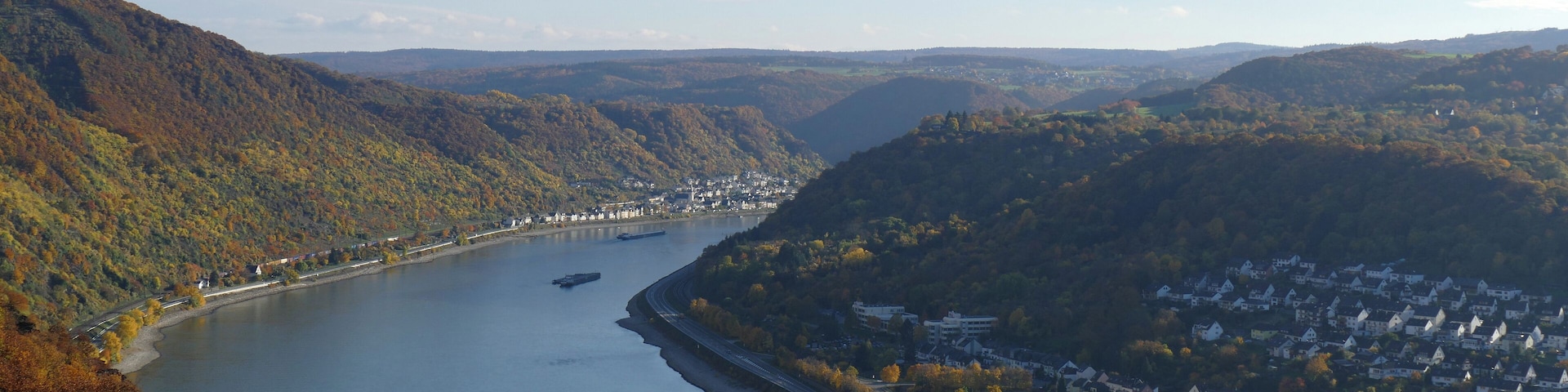 A river winding through a valley with a town on one side and hills on the other.