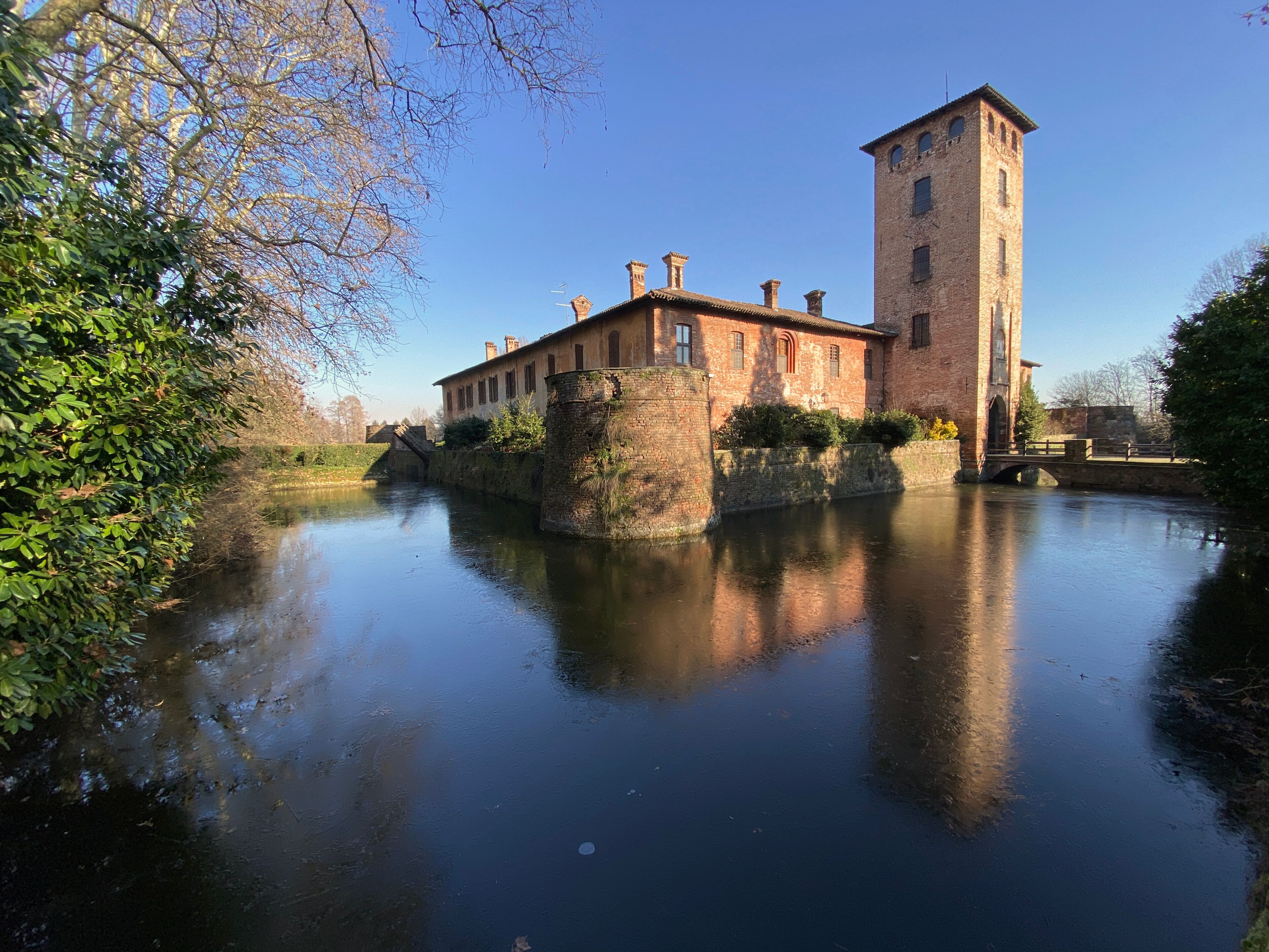 Un bâtiment historique doté d’une tour, situé au bord d’une rivière paisible.