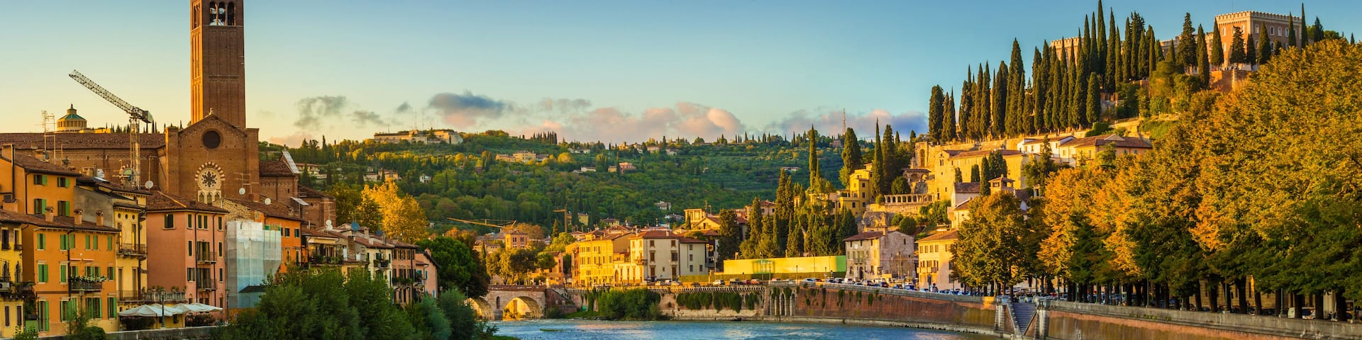 A river with a bridge, a tower, and buildings on a hillside.