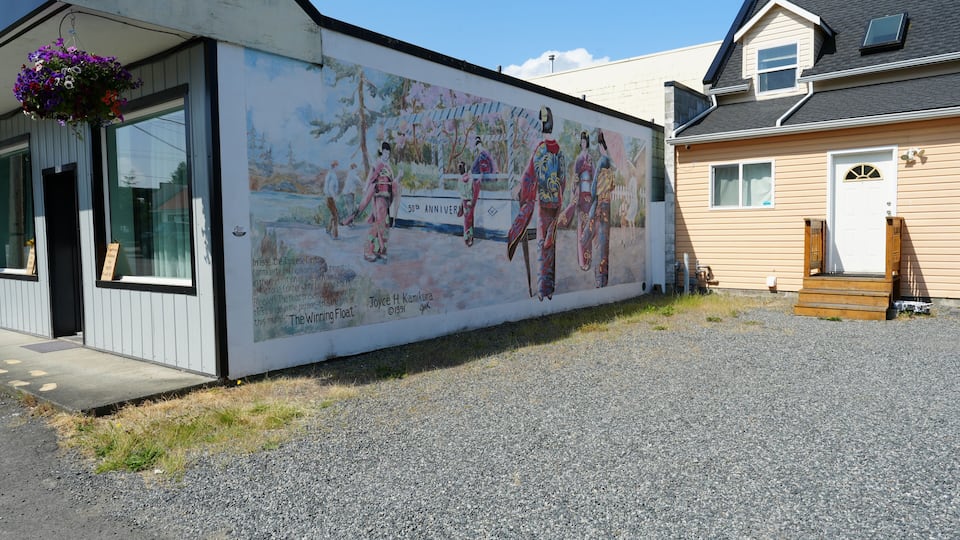 A building with a mural depicting historical figures and a sign indicating a 50th anniversary.