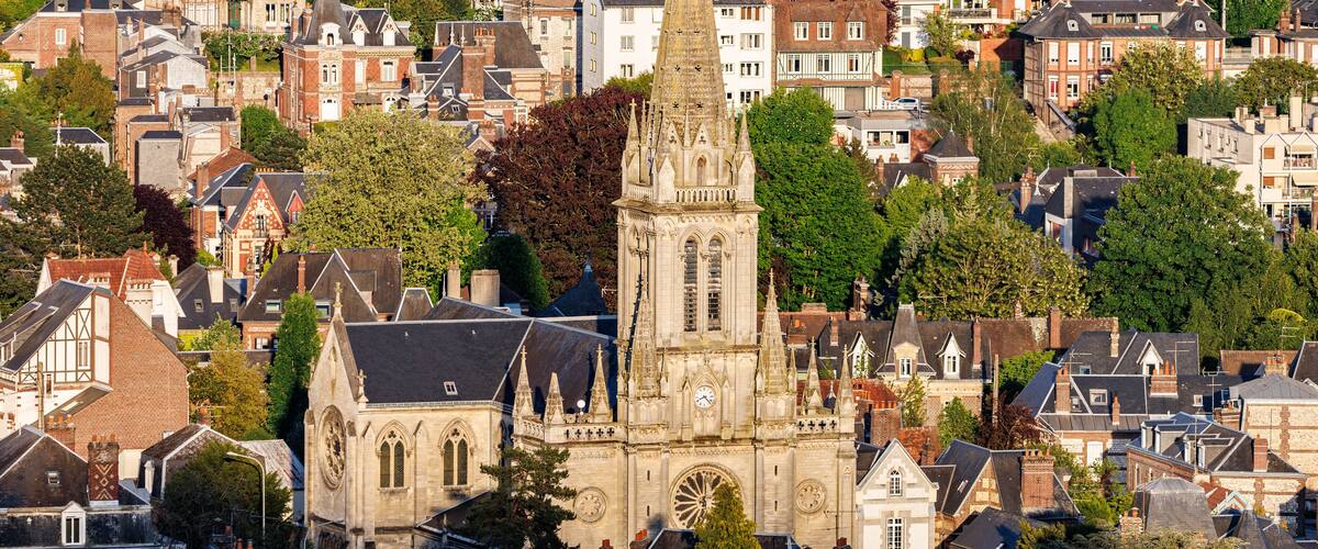 A historic church with a tall spire surrounded by residential buildings and trees.