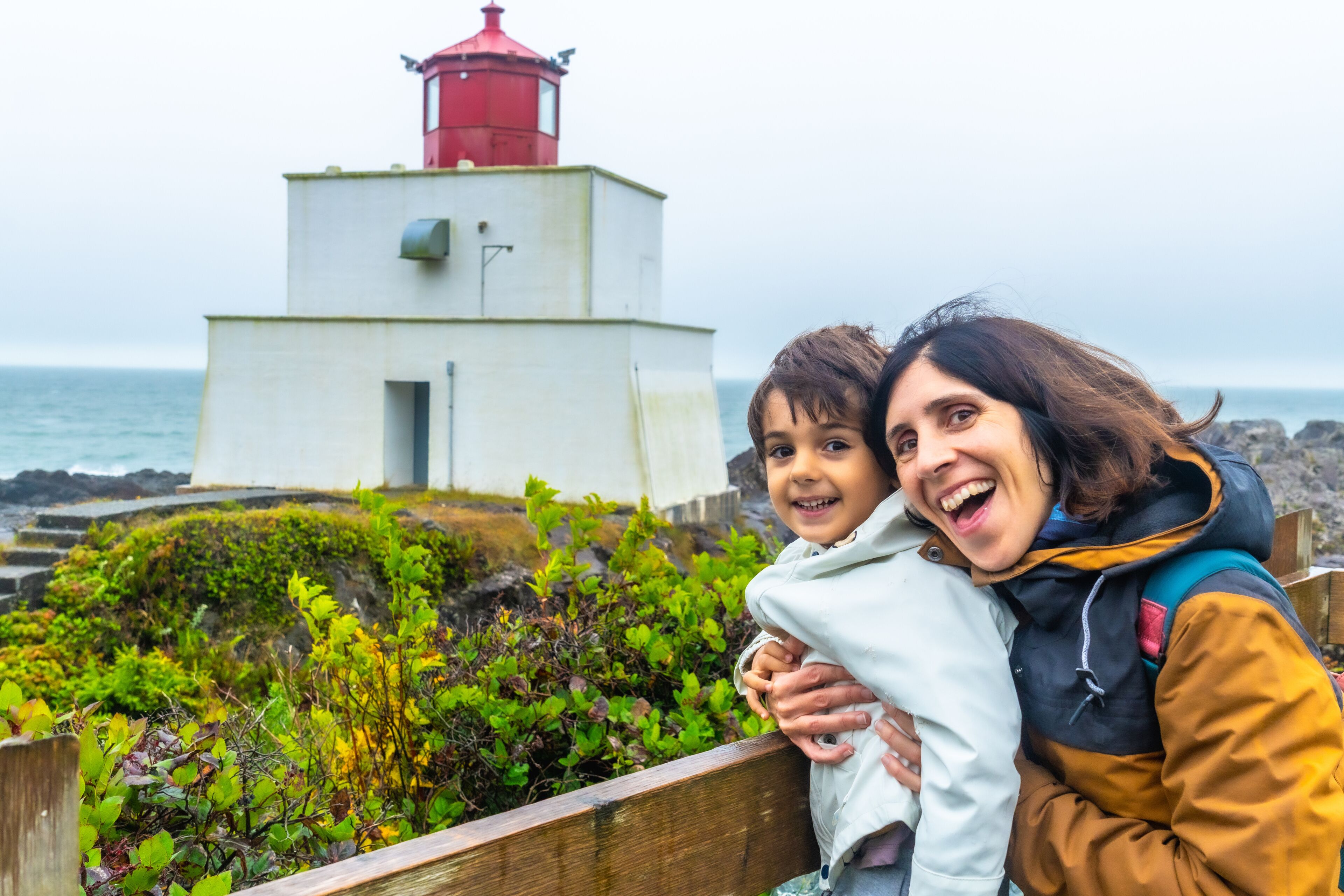 A lighthouse, rocky shoreline, and greenery.