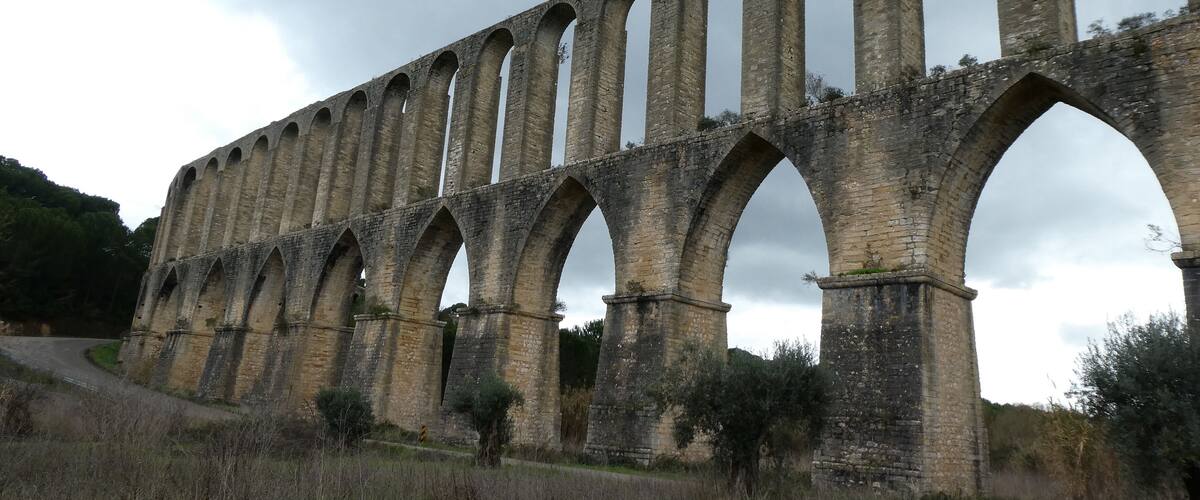 A large stone viaduct with multiple arches spanning a road.