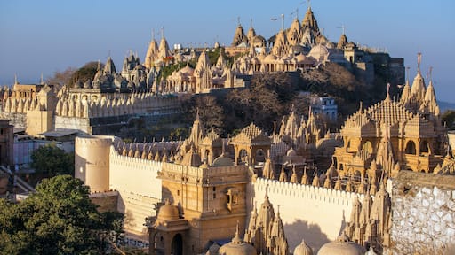 A large, ornate temple complex with multiple spires and domes, situated on a hill with a clear sky above.