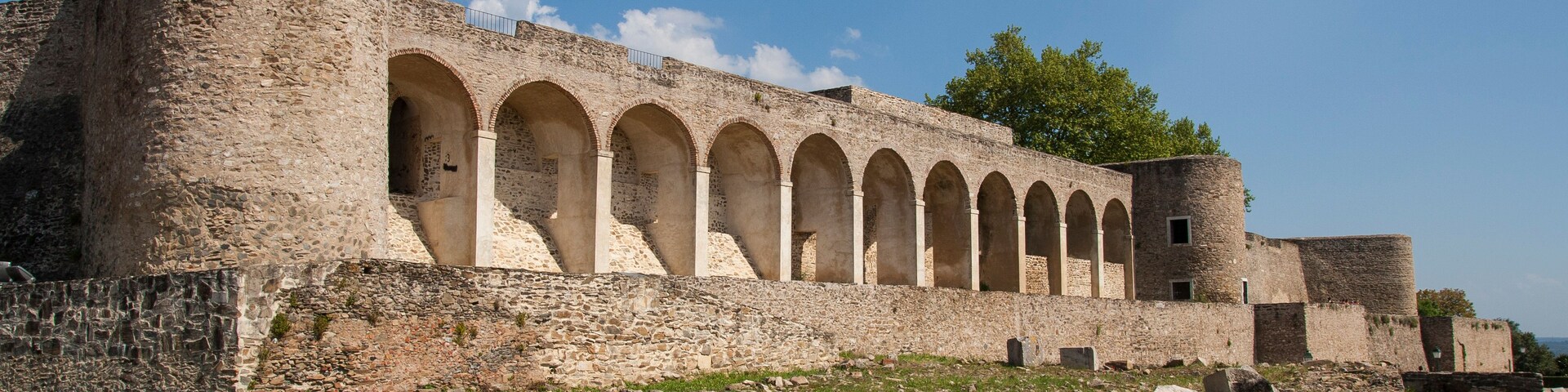 Eine historische Steinkastelle mit Rundbogen-Gängen und einem markanten Turm.