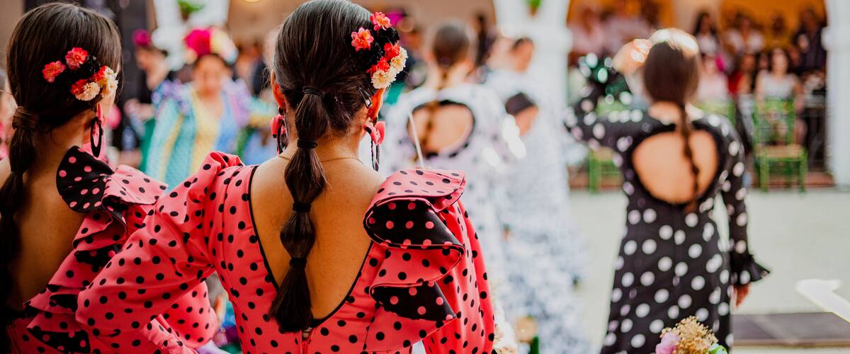 A group of people in polka dot dresses at an indoor event with arches and hanging decorations.
