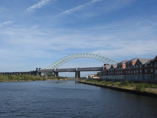 A bridge over a river with buildings on the right bank.