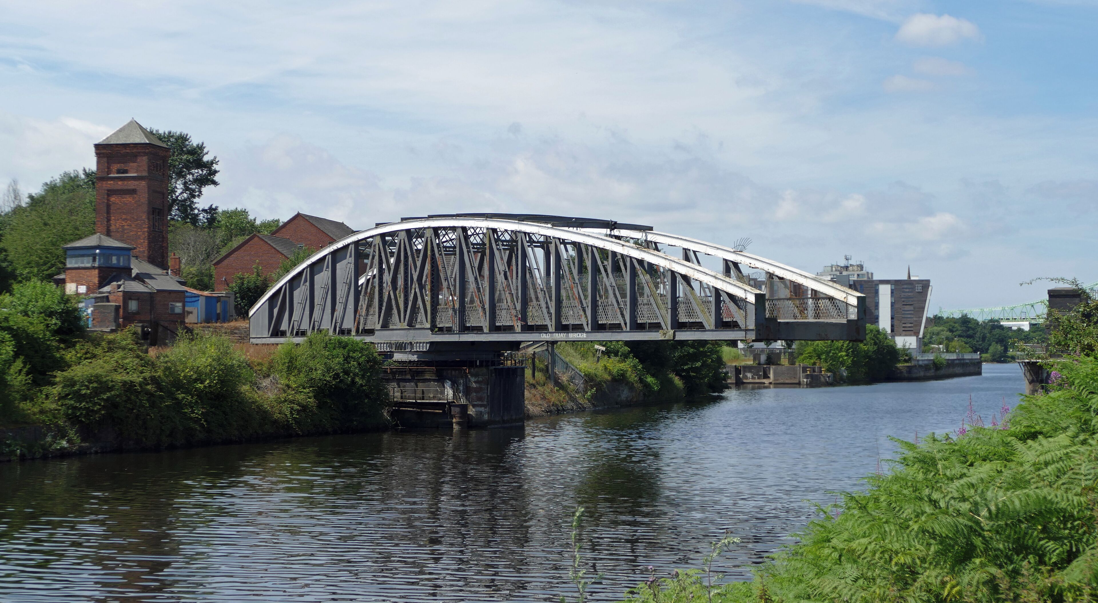 The Old Quay Bridge, in Runcorn, is a circa 1894 swing bridge along the Manchester Ship Canal. In this view, from the northeast, it is starting to swing open to allow a ship to pass.