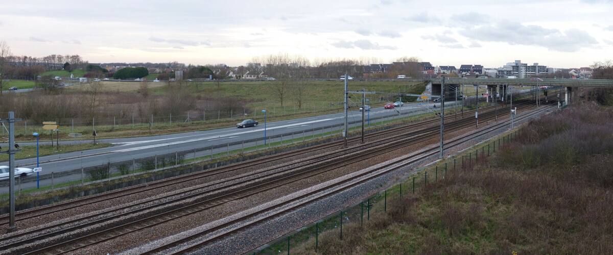 A railway crossing with multiple tracks and a road overpass.