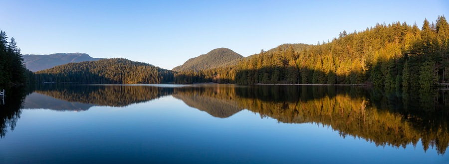 Beautiful and Vibrant panoramic view of a lake surounded by Canadian Mountain Landscape during sunset. Taken in White Pine Beach, Port Moody, Vancouver, British Columbia, Canada. Panorama