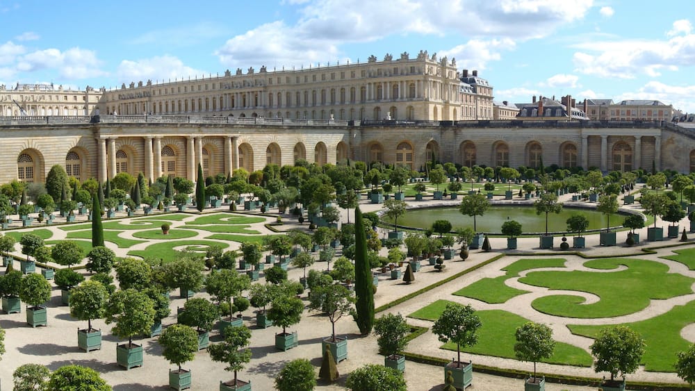 A grand palace with symmetrical gardens and a central pond.