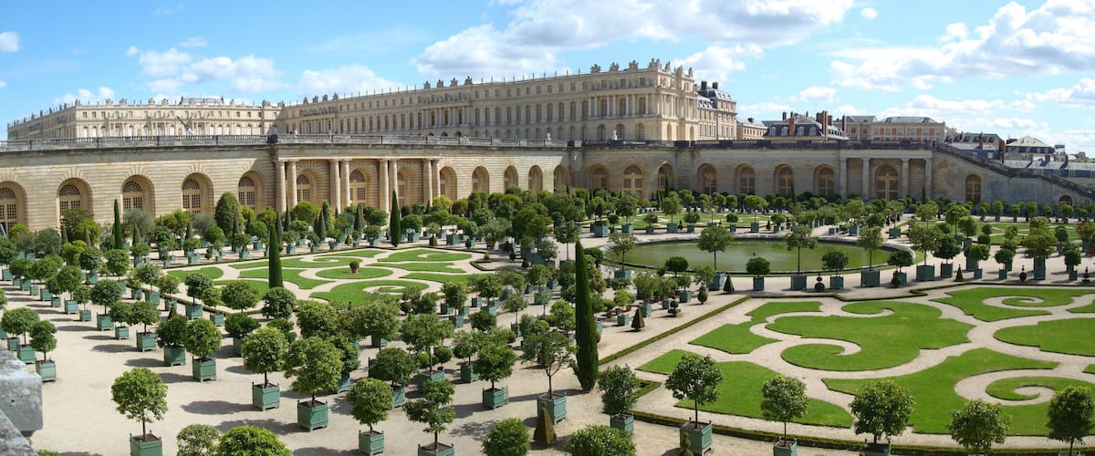 A grand palace with symmetrical gardens and a central pond.