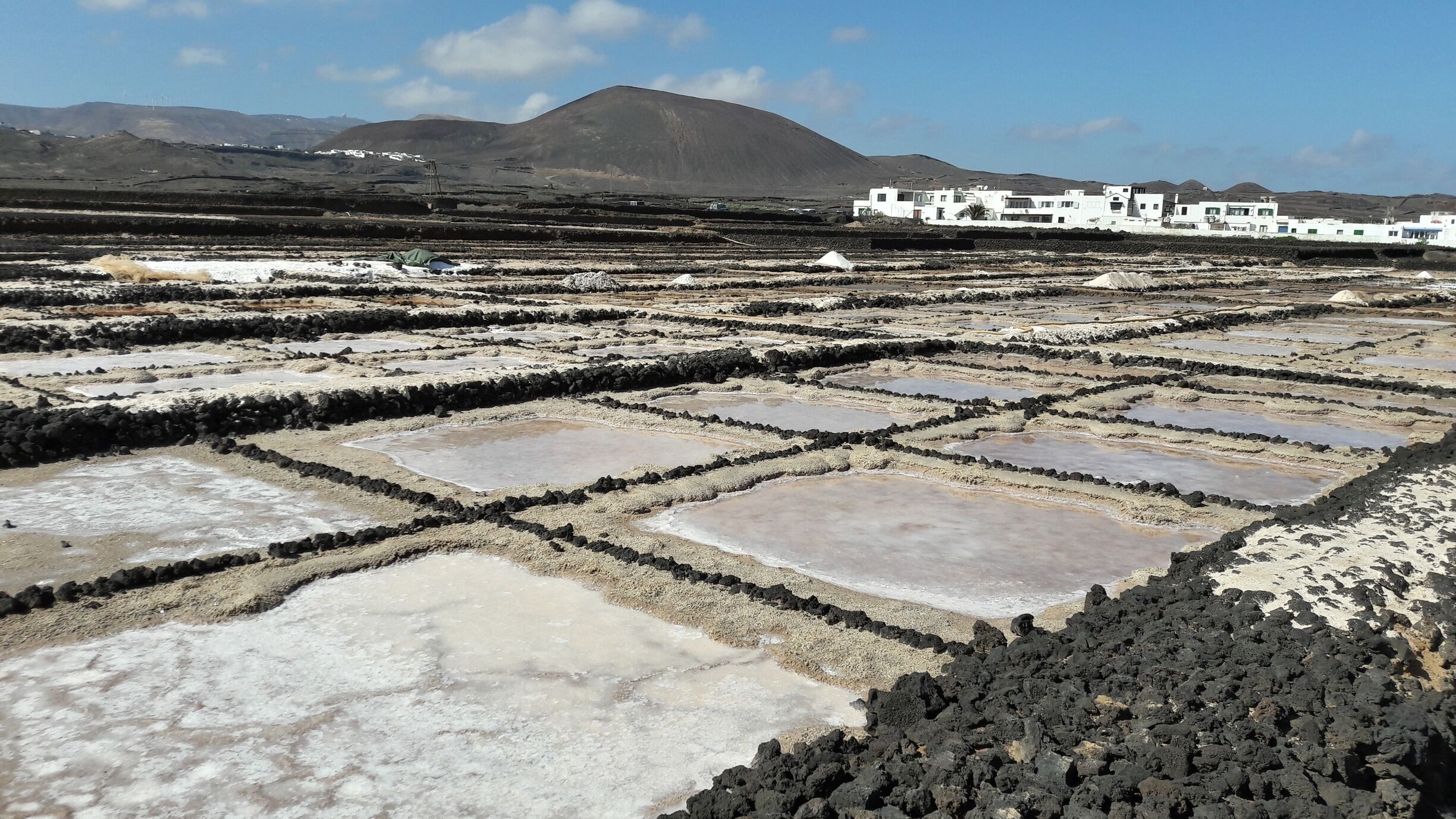 Terraced salt flats with white buildings in the background.
