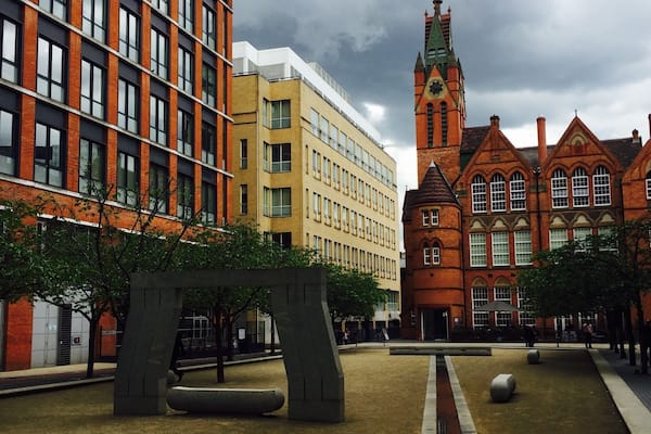 Une cour intérieure avec un bâtiment moderne, une église historique et un chemin pavé de briques.