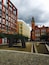 A courtyard with a modern building, a historic church, and a brick pathway.