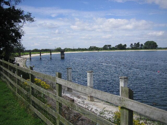 Shustoke reservoir. The west end of Shustoke reservoir. This reservoir boasts a circular walk and a car park for walkers to use.