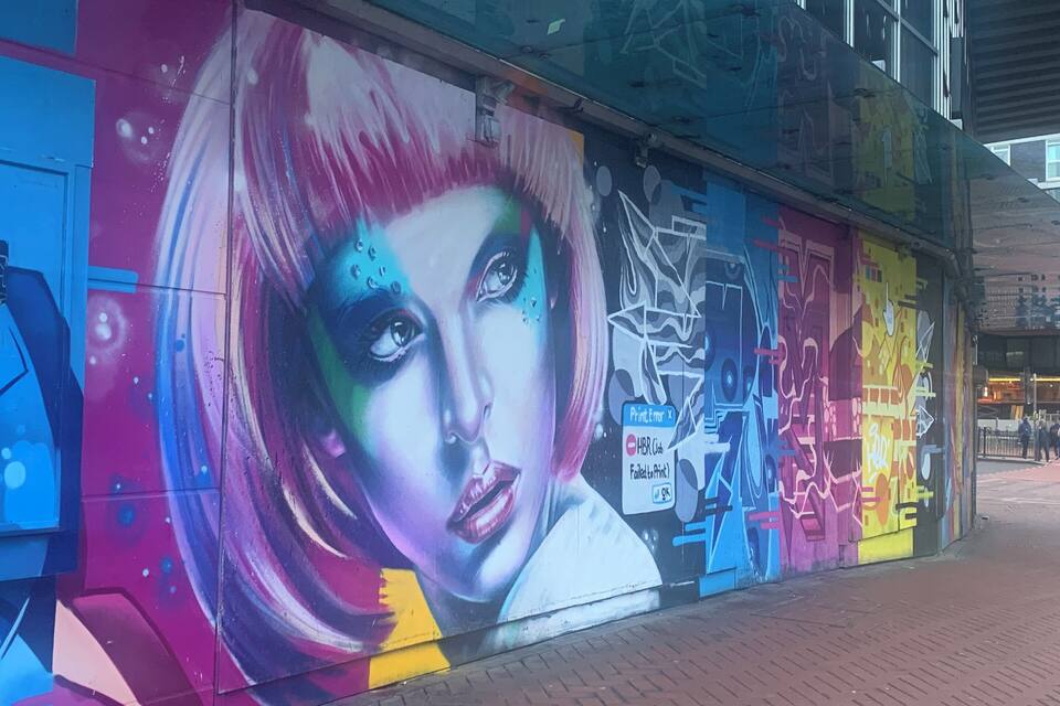 A colorful mural with abstract designs and graffiti on a building wall.