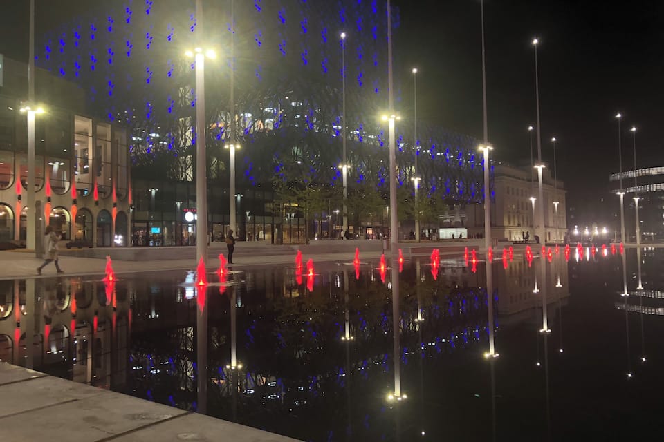 Een verlicht stadsgezicht 's nachts, met glinsterende gebouwen en straatverlichting.