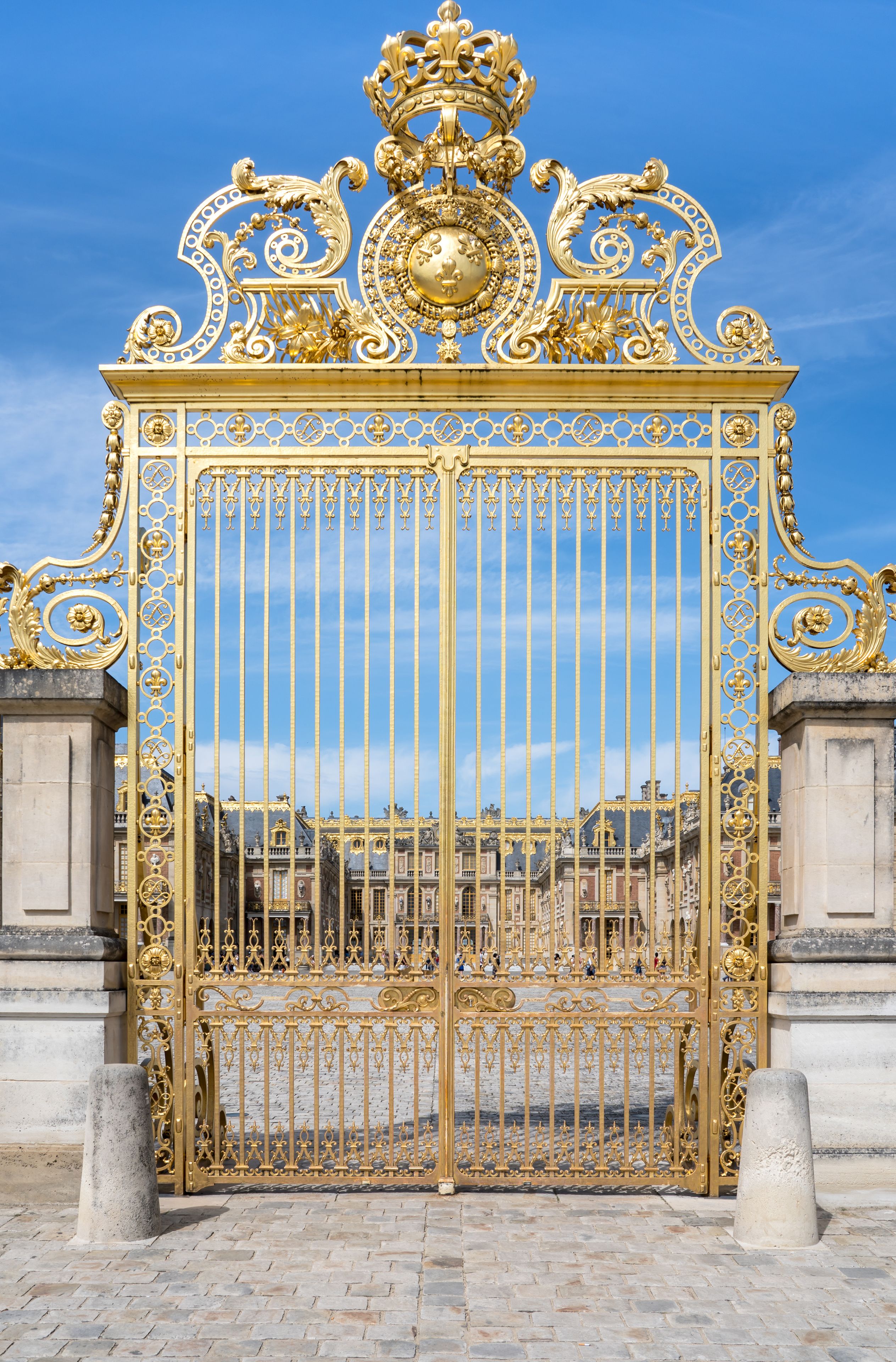 Un maestoso cancello dorato con decorazioni elaborate e un cielo blu limpido sullo sfondo.