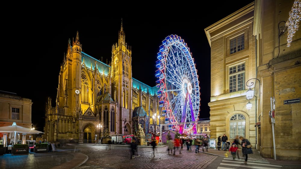 Une cathédrale historique, avec une grande grande roue illuminée en arrière-plan.