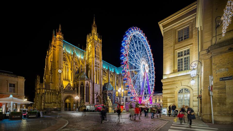 A historic cathedral with a large illuminated Ferris wheel in the background.