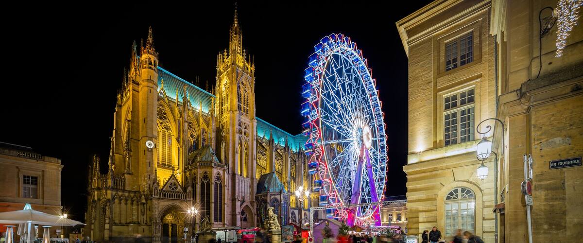 A historic cathedral with a large illuminated Ferris wheel in the background.