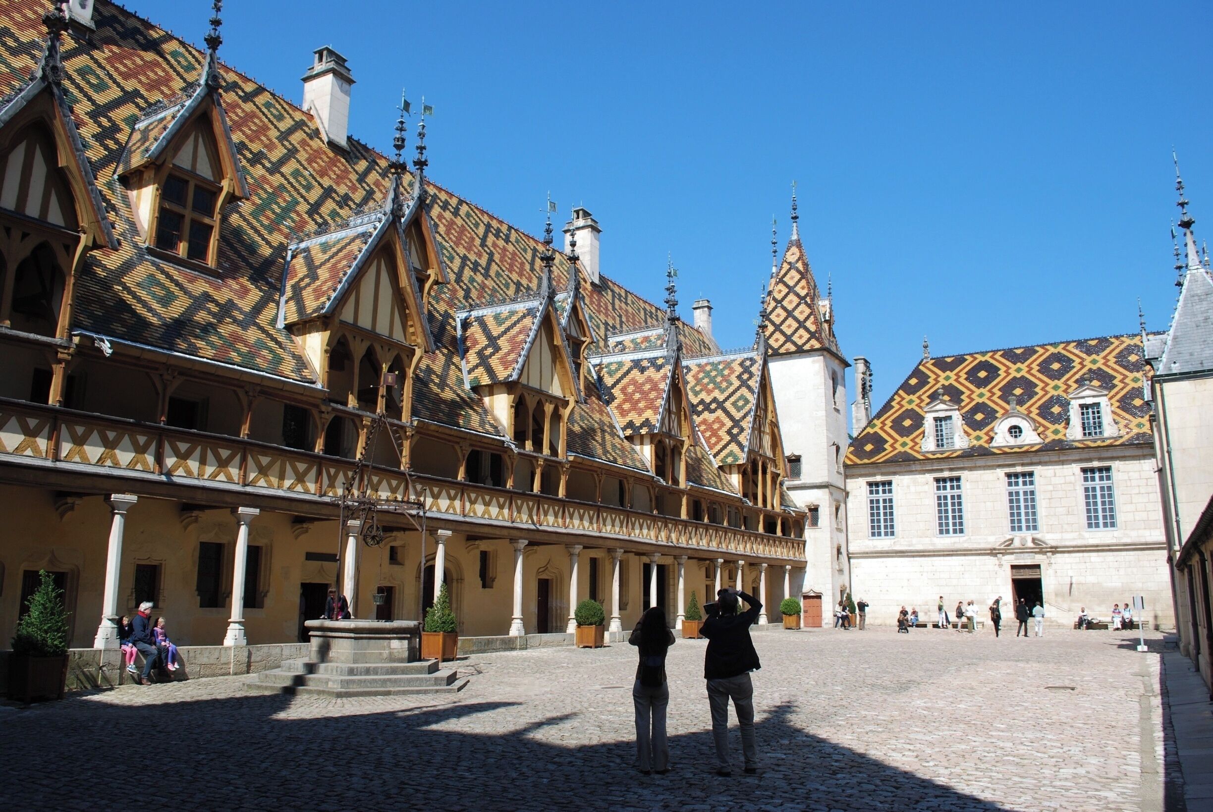 A historic courtyard with ornate buildings, a cobblestone ground, and a fountain.