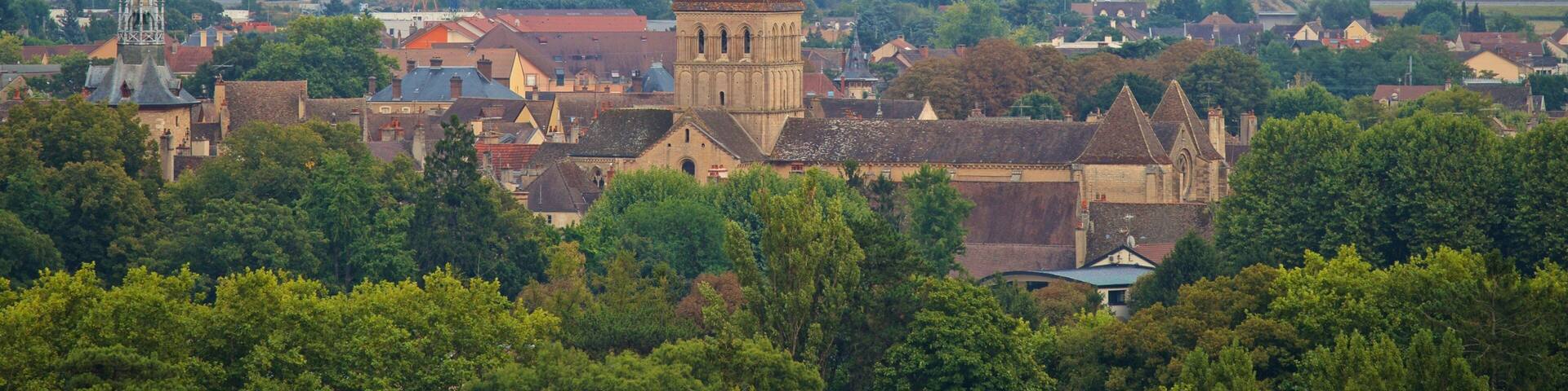 A town with a prominent church tower, lush greenery, and a hot air balloon in the sky.