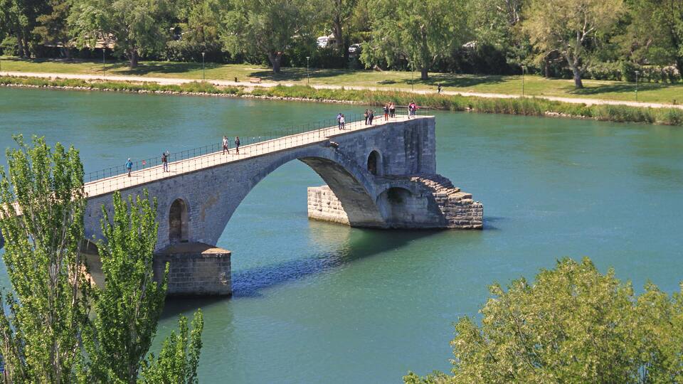 A stone bridge over a river with people walking on it.