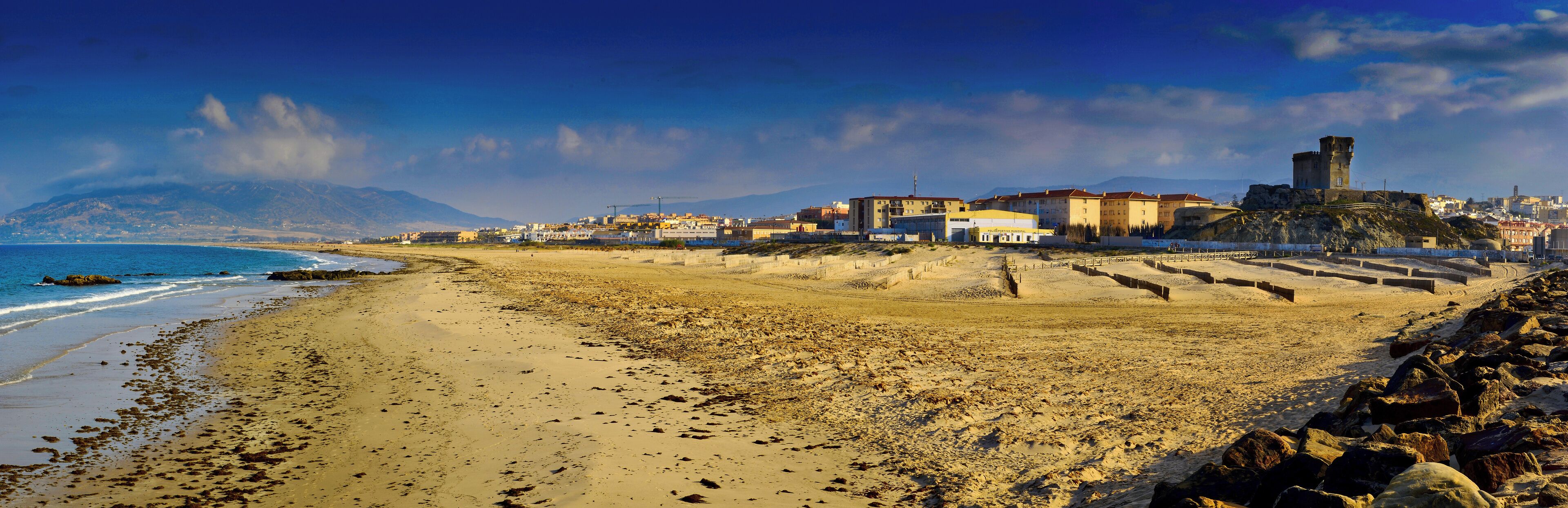 A coastal town with a beach, buildings, and a castle.