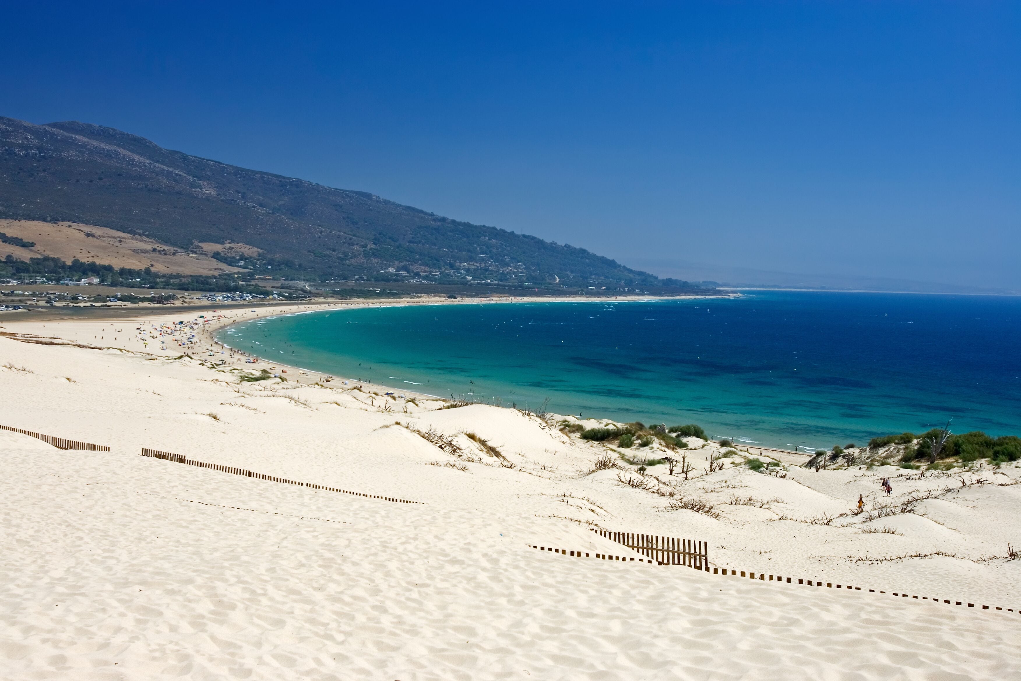 Old wooden fence on deserted white sandy beach dunes on a hot sunny day in Tarifa Spain
