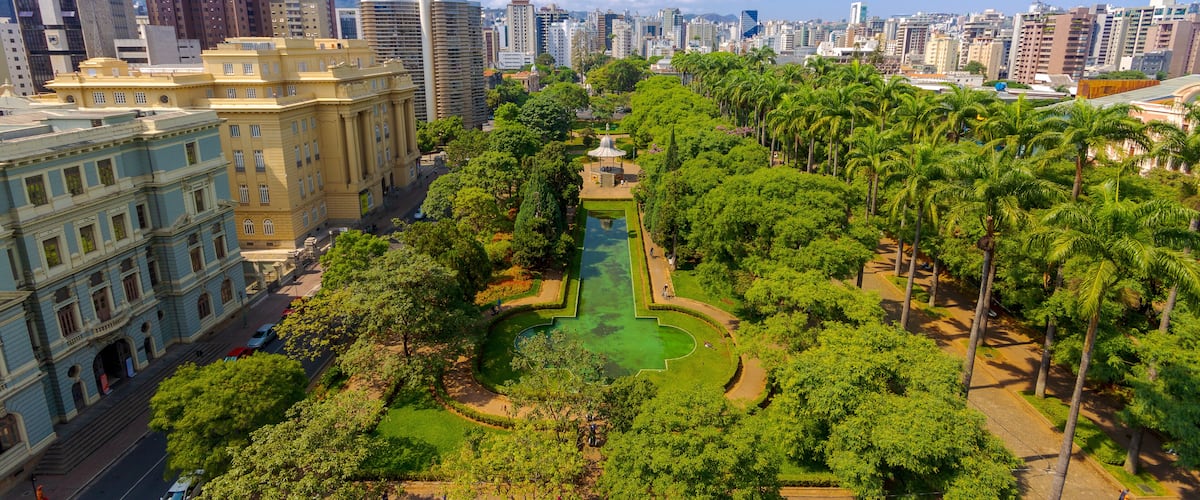 Paisagem urbana com um parque central, que inclui um lago, edifícios altos e palmeiras.
