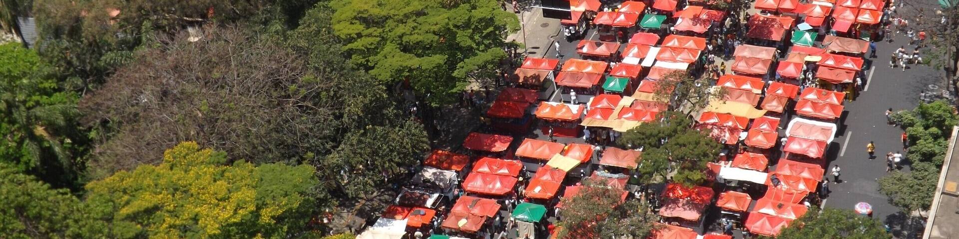 An aerial view of a densely packed outdoor market with numerous stalls covered by colorful umbrellas.