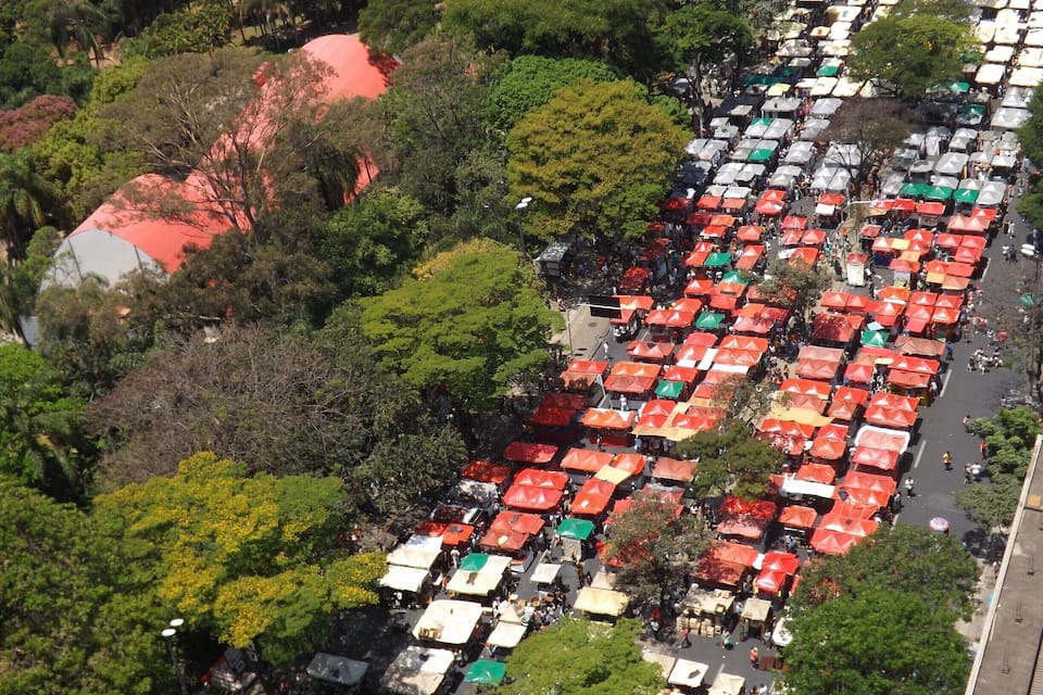 Vista aérea de un mercado al aire libre muy concurrido, con numerosos puestos cubiertos por sombrillas de colores.