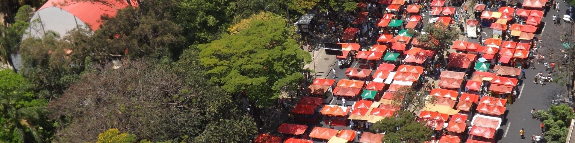 Vista aérea de un mercado al aire libre muy concurrido, con numerosos puestos cubiertos por sombrillas de colores.