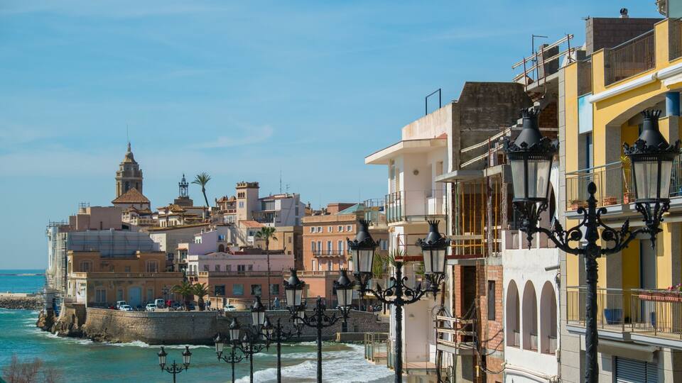 A coastal town with historic buildings, a sea wall, and ornate street lamps.