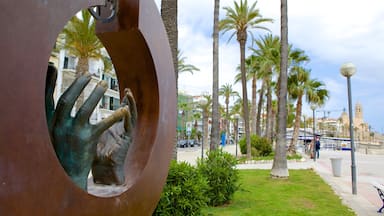 Una escultura de una mano sosteniendo una llave, palmeras y un paisaje urbano costero.