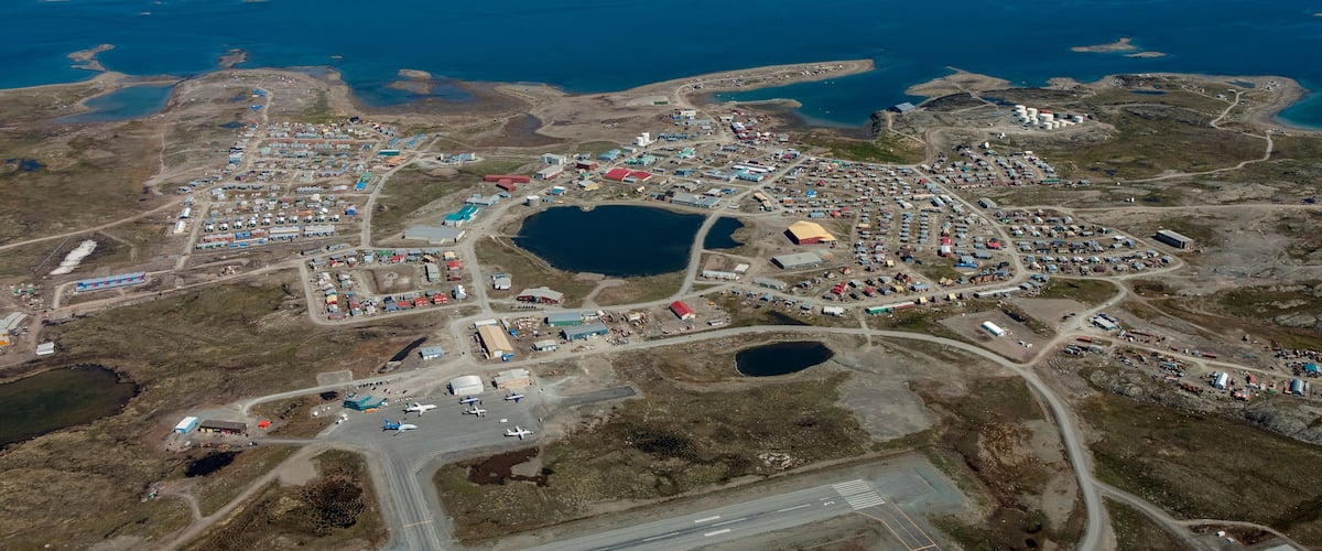 An aerial view of a coastal town with a harbor, several buildings, and a large body of water.