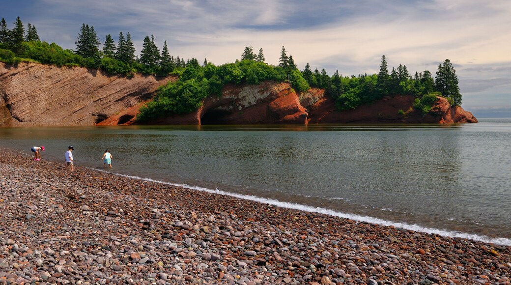 Children playing on pebble beach at sea caves of St Martins New Brunswick at Bay of Fundy high tide