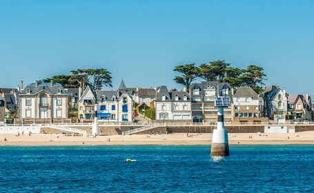 Une ville côtière dotée de bâtiments historiques, d’une plage de sable et d’un phare situé en mer.