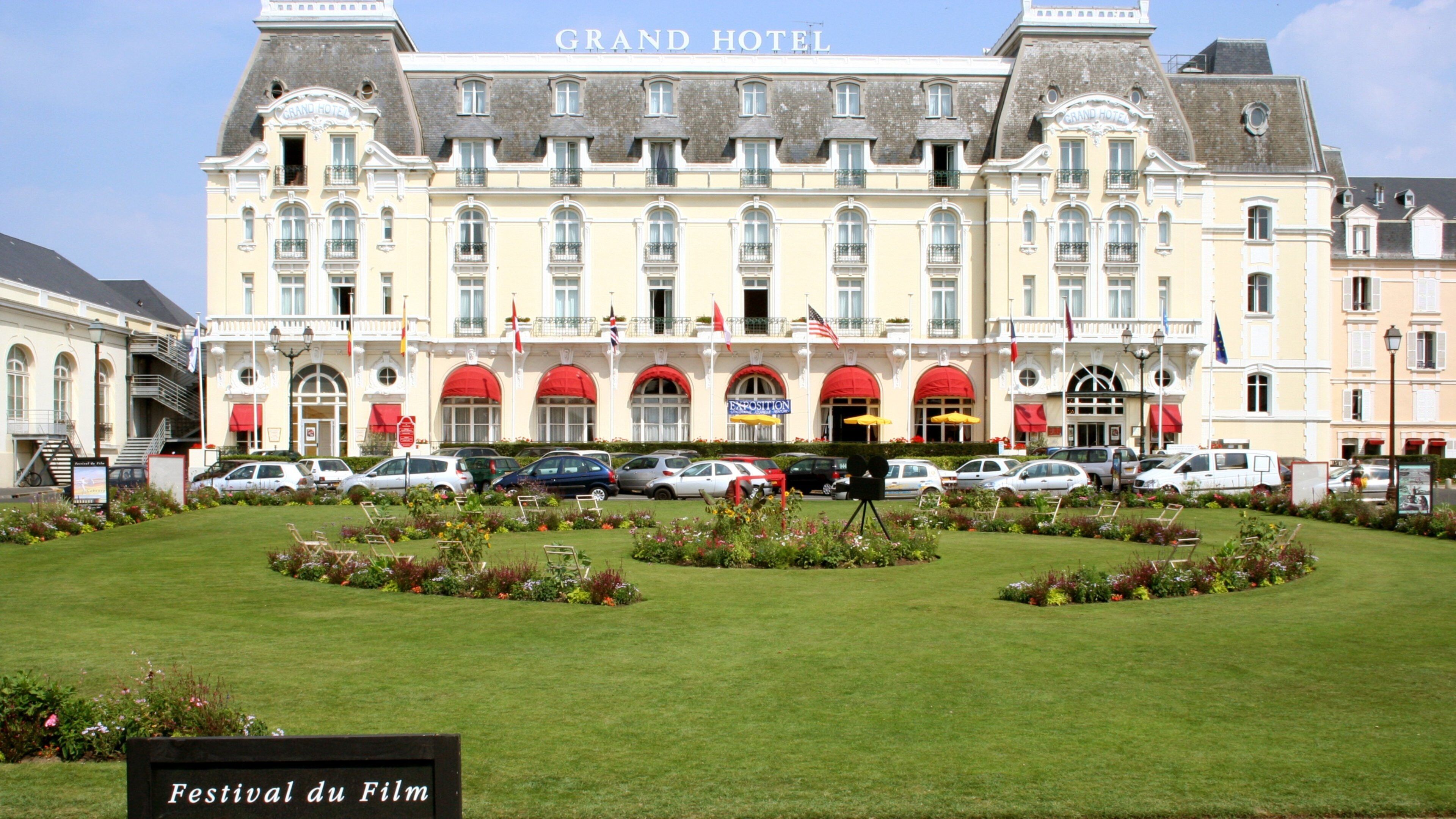 A large hotel with a garden in front.