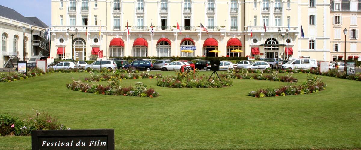A large hotel with a garden in front.